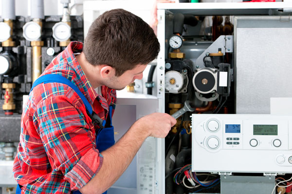 HVAC technician inspecting and repairing boiler controls in Firestone