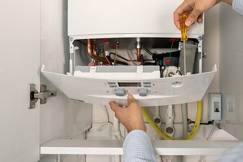HVAC technician repairing an indoor boiler in Firestone