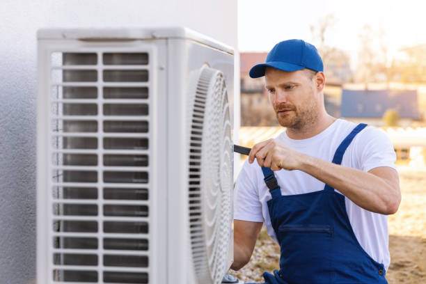 HVAC technician servicing an outdoor air conditioning unit in Firestone