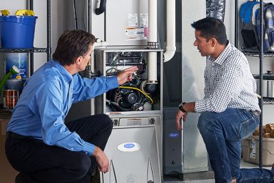 HVAC technician explaining furnace repair and maintenance to a homeowner in Firestone, CO