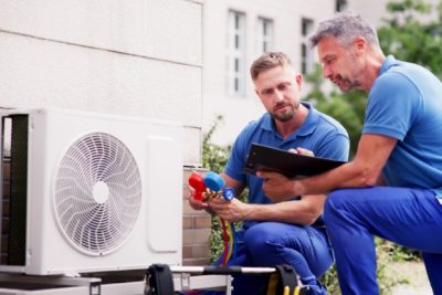HVAC technicians reviewing an outdoor air conditioning unit in Firestone, CO