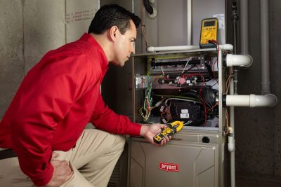 Heating and air conditioning technician servicing an indoor furnace in Firestone, CO